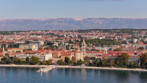 Video - Aerial drone view of Zadar's waterfront and historic Old Town, with St. Anastasia Cathedral's bell tower prominently visible