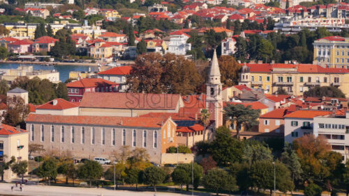 Video - Aerial drone view of Zadar's waterfront and historic Old Town, with St. Anastasia Cathedral's bell tower prominently visible