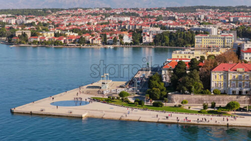 Video - Aerial drone view of Zadar's famous Greeting to the Sun installation on the pier, with people walking along the Riva promenade