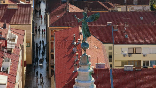 Video - Aerial drone view of a bronze angel statue standing atop a church spire in Zadar's Old Town