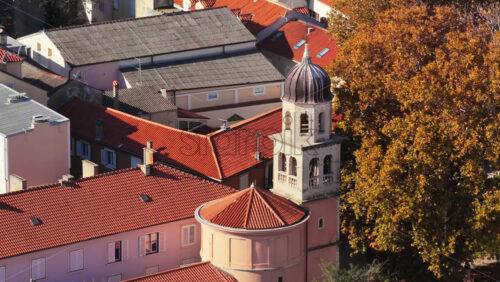 Video - Aerial drone view of a small historic church with a rounded apse and a stone bell tower topped with a dark dome. Zadar, Croatia
