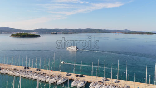Video - Aerial drone view of a large marina packed with boats and sailboats, with calm blue water and distant islands. Biograd na Moru, Croatia