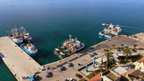 Video - Aerial drone view of a concrete pier with several fishing vessels and workboats docked along the edge. Biograd na Moru, Croatia