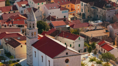 Video - Aerial drone view St. Anastasia's Church, focusing on its Romanesque stone bell tower surrounded by typical Dalmatian residential architecture. Biograd na Moru, Croatia