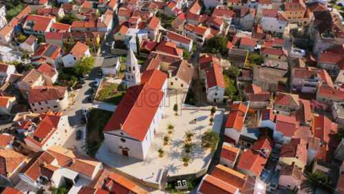 Video - Aerial drone view of Biograd's seaside neighborhood with narrow streets, Mediterranean homes, and glimpses of the waterfront lined with palm trees and moored small boats. Biograd na Moru, Croatia
