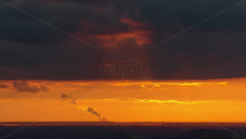 Video - Aerial drone view of Belgrade with the silhouette of a distant industrial plant and smokestack emitting clouds of steam