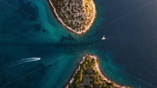 Video - Aerial drone view of the Tribunj archipelago showing vibrant turquoise water flowing between rocky Adriatic islands. Croatia