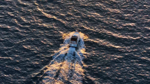 Video - Aerial drone view of a boat riding at sunset.
