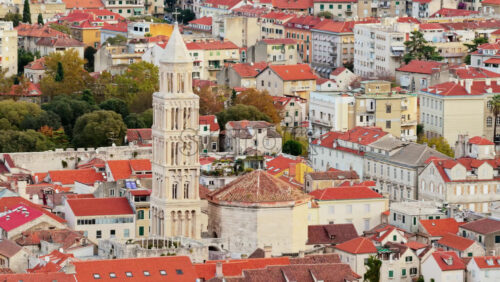 Video - Aerial drone view of the iconic bell tower of Split rising above red rooftops with mountains in the background