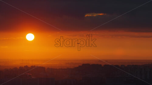 Video - Aerial drone view of a sunset above Belgrade, Serbia, with deep orange tones and an airplane passing across the sky