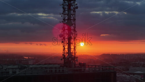 Video - Aerial drone view of a large telecommunications tower set against an intense orange sunset over Belgrade, Serbi
