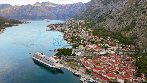 Video - Aerial drone view of the old town, the port, and a cruise ship in the bay, framed by steep mountains and clear morning light in the bay of Kotor