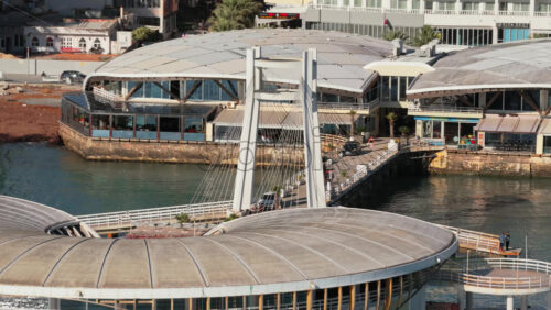 Video - Aerial drone view of the iconic bridge building extending over the turquoise waters of the Adriatic Sea in Durres, Albania