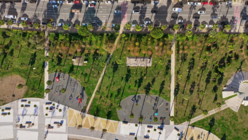 Video - Aerial drone view the green waterfront park, tall residential towers, sports courts, and the large industrial port in the distance in Durres, Albania