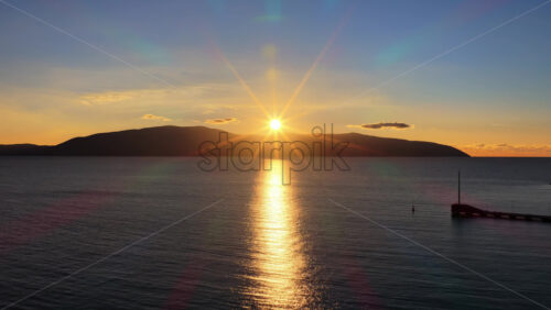 Video - Aerial drone view of a sunset across the calm Adriatic Sea as the sun dips behind the mountains. Vlora, Albania