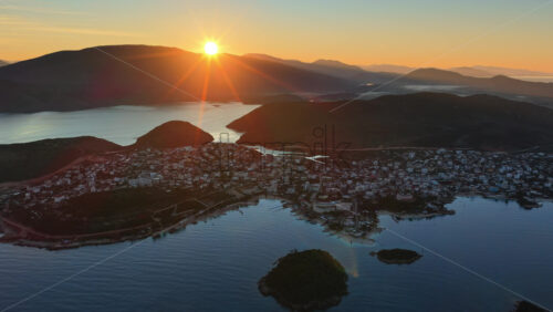 Video - Aerial drone view of a fisherman rowing through deep turquoise waters along the Ksamil, Albania coastline, with nets and equipment visible on the rustic boat