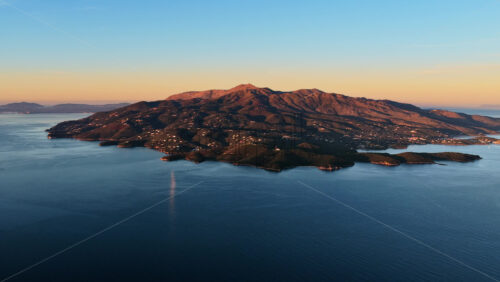 Video - Aerial drone view of Corfu island near Ksamil, Albania showing rugged landscapes, green vegetation, and the island's coastline bathed in soft sunrise light