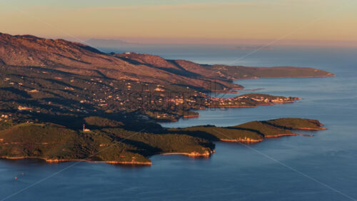Video - Aerial drone view of the Corfu Island from Ksamil, Albania, revealing winding waterways, small islands, shallow wetlands, and the coastal landscape during warm sunrise light