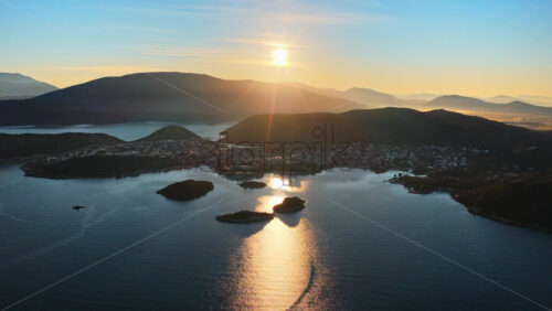 Video - Aerial drone view of the Ksamil Islands, with the sun reflecting on the sea and the small islets casting long shadows across the shimmering water