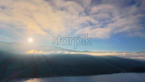 Video - Aerial drone view of the sun rising over Mount Galicica, casting golden light over the mountains and Lake Ohrid below