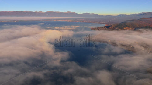Video - Aerial drone view of a Galichica mountain ridge rising above a sea of clouds, with soft layers of fog covering the valley below