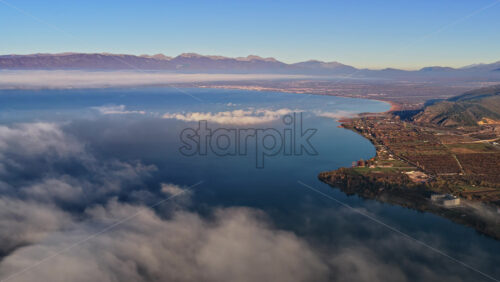 Video - Aerial drone view of a Galichica mountain ridge rising above a sea of clouds, with soft layers of fog covering the valley below