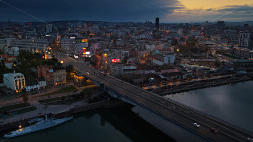 Video - Belgrade, Serbia - November 10, 2025: Aerial drone view of Belgrade's bridges and the Sava River during dusk, capturing light reflections on the water and traffic movement along the riverbank
