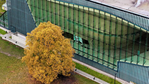 Video - Warsaw, Poland - October 30, 2025: Aerial drone view of the POLIN Museum of the History of Polish Jews in the Muranow district, showing its iconic curved glass facade and modern architecture surrounded by autumn trees