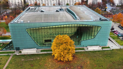 Video - Warsaw, Poland - October 30, 2025: Aerial drone view of the POLIN Museum of the History of Polish Jews in the Muranow district, showing its iconic curved glass facade and modern architecture surrounded by autumn trees