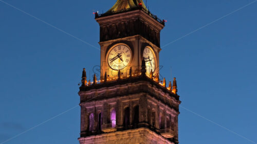 Video - Aerial drone view of the Palace of Culture of Warsaw and Science, glowing with colorful lights among the surrounding skyscrapers in the evening