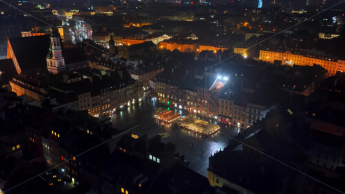 Video - Aerial drone view of Warsaw's Old Town toward the Srodmiescie district, with bright city lights and residential buildings visible below
