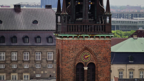 Video - Church tower with a visible clock against city buildings. Copenhagen, Denmark