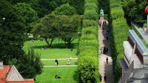 Video - Copenhagen, Denmark - August 4, 2025: People relaxing and walking through a public park with lush green lawns and hedges