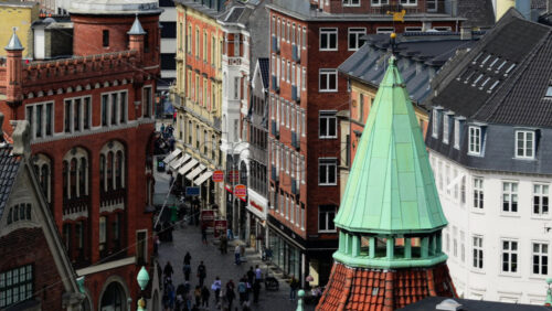 Video - Copenhagen, Denmark - August 4, 2025: Green domed spire rising above historic buildings and a bustling pedestrian street