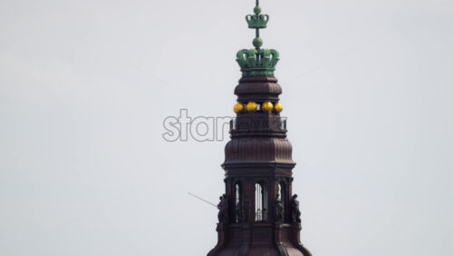 Video - Christiansborg Palace tower with multiple ornate crowns under a cloudy sky