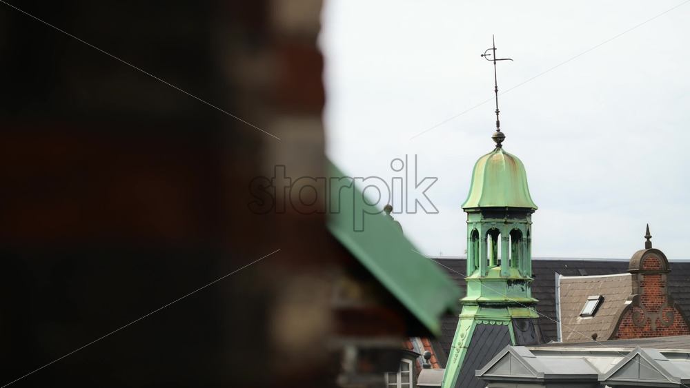 Video - Weathered green copper cupola and weather vane topping a historic building spire. Copenhagen, Denmark