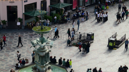 Video - Copenhagen, Denmark - August 3, 2025: Public square with people walking and relaxing near the stork fountain on a sunny day