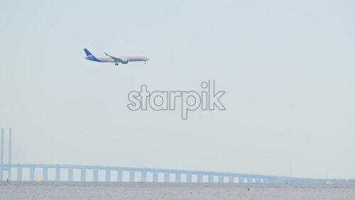 Video - Copenhagen, Denmark - August 4, 2025: Airplane flying low over the ocean with the Oresund Bridge in the background