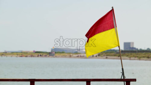 Video - Lifeguard flag waving on a sunny beach, indicating a patrolled swimming area. Copenhagen, Denmark