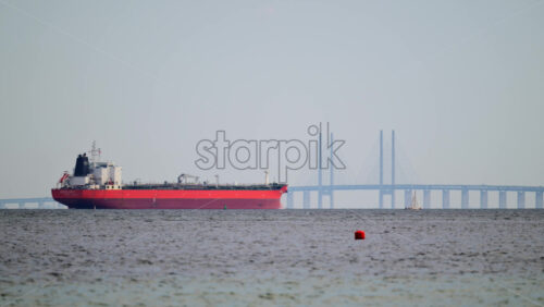 Video - Red tanker sailing along the Oresund Strait with the iconic Oresund Bridge in the background. Copenhagen, Denmark