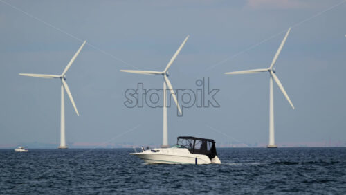 Video - Motorboat traveling on the ocean with offshore wind turbines generating clean energy in the background. Copenhagen, Denmark