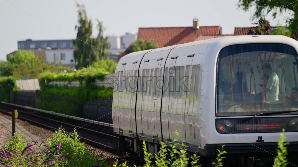 Video - Copenhagen, Denmark - August 4, 2025: Modern commuter train traveling along railway tracks on an elevated line in a city