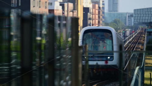 Video - Copenhagen, Denmark - August 5, 2025: Automated metro train moving along elevated tracks through a modern city district