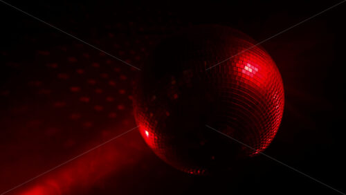 Video - Disco ball reflecting glowing red light spots on a dark background, creating a festive party atmosphere