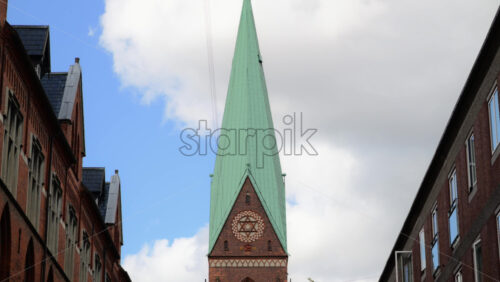 Video - Brick church tower and clock standing between residential buildings in a city. Copenhagen, Denmark