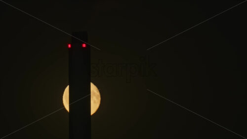 Video - Tall Copenhill chimney building tower silhouetting a large full moon in a dramatic dark sky. Copenhagen, Denmark
