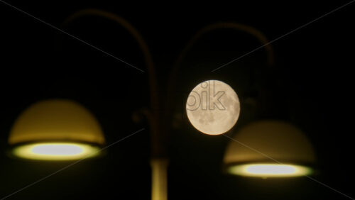 Video - Full moon glowing behind a street light in a dark urban night scene, creating contrast. Copenhagen, Denmark