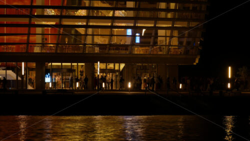 Video - Copenhagen, Denmark - August 5, 2025: Opera House lights reflecting on the water at night with people gathering outside