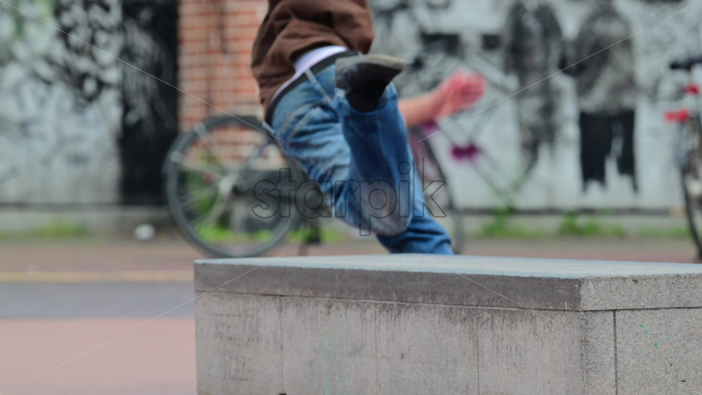 Video - Skater riding skateboard and performing a trick near a concrete ledge in an urban setting. Falling down