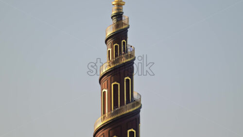 Video - Baroque spire of the Church of Our Saviour rising above green trees against a clear sky. Copenhagen, Denmark